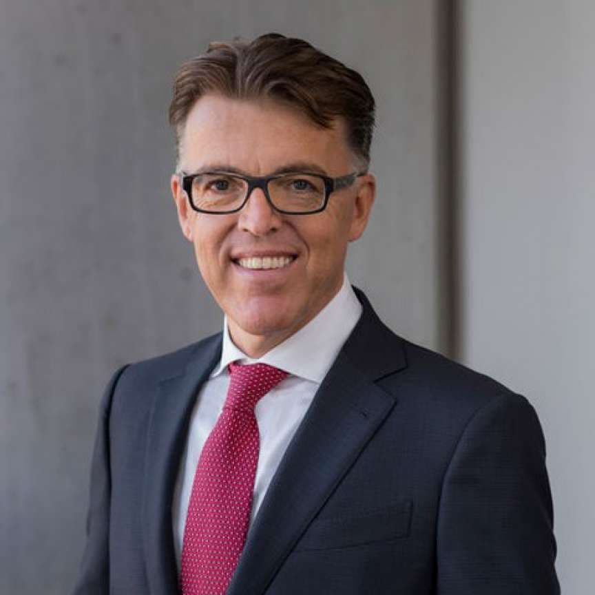 A smiling volunteer tutor in glasses and a suit, ready to teach